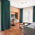 Moderná obývacia časť apartmánu s jedálenským stolom, televízorom a veľkými oknami