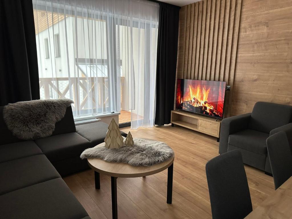 Moderná obývacia izba apartmánu s balkónom, pohodlným sedením a televízorom