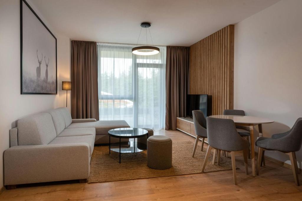 Moderná obývacia izba apartmánu s pohodlnou sedačkou, jedálenským kútom a veľkým francúzskym oknom.