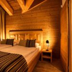 Spálňa apartmánu DaSus Lux&Wellness Apartments Sosana s drevenými stenami, manželskou posteľou a nočnými stolíkmi.