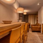 Priestranná jedáleň s dreveným stolom a plne vybavenou kuchyňou v apartmáne Sosana