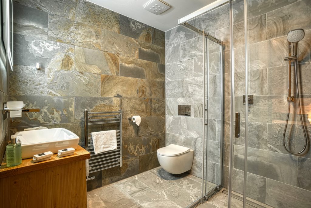 Elegantná kúpeľňa so sprchovým kútom, umývadlom a kamenným obkladom v apartmáne Sosana