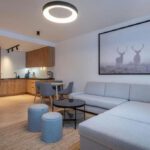 Priestranná obývacia izba s rohovou sedačkou, jedálenským stolom a modernou kuchyňou v apartmáne DaSus Luxury Tále.